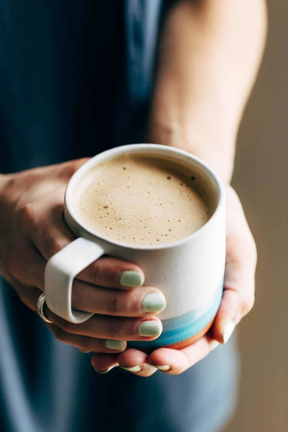 Hands holding a mug of Cashew Coffee. this recipe Featured comment Possibly the best coffee I’ve ever had in my life! Without a doubt, it’s creamy, nutty & so satisfying. Cashew coffee will change your life!! Pinch of Yum Logo Ashley 263 more comments Two words: CASHEW COFFEE. Oh my word, you guys. This could be – has been – is currently – a game changer in our collective coffee lives. It fits anywhere and everywhere into your life because when something is so luxuriously creamy, nutty, and sweet with a bite of salt, how can it not be? For example. It’s 6am and you’re getting up for an early work meeting, and you’d like to not hate the next two hours of your life. CASHEW COFFEE. It’s 10am and you work from home and it’s kind of rainy, so naturally a cozy pre-lunch pick-me-up becomes necessary. CASHEW COFFEE. It’s 2pm and you’re a stay-at-home mom and the kids are finally napping (I used to be a full-time nanny and I semi-know this feeling), and you want to give yourself a hug in celebration of fifteen minutes to yourself. CASHEW COFFEE. Holy creamy goodness. This is heaven-sent. Cashew Coffee in two mugs. About a year and a half ago, I made an important discovery with a tiny bit of help from my friend aka counselor: maybe it’s for the best if I don’t drink coffee. It’s one of those things you always think about, right? You always say that you should probably start cutting back on coffee, pop, caffeine, whatever… but for some people it’s not so much a thing-would-be-nice-to-do thing and more of a this-is-really-important-for-my-overall-well-being kind of thing. I found out last year that I am that person. Hi. Nice to meet you. I have some perfectionist, anxious, zero chill tendencies (gasp) and caffeine makes my brain WORSE, not better. If I am already a high-strung person, caffeine just takes the high-strung-ness to new heights that should not be humanly experienced. When I stopped drinking coffee, or more accurately, swapped my default morning coffee for the occasional decaf latte or Americano or – get this – MORE WATER, I found that my overall well-being dramatically leveled out. For those not familiar with being constantly in overdrive, leveling out is a good thing. It means calm. Normal. Eyes not bulging out of head, hair not standing on end, life not spinning wildly out of control. So I do love good coffee. Big fan over here. I still try to stay away from regular coffee for big-picture wellness reasons, but I love a deep, dark, mildly creamy cup of decaf in the morning. My two rules are that it has to be good coffee, and it has to be decaf. This is where my beloved (decaf) coffee journey will now merge with an old, trusted friend: wrinkly, buttery, roasted cashews. Cashews close up. That’s right, I just said cashews. Here’s the secret that will unlock some morning magic for you: You can, in fact, BLEND CASHEWS INTO YOUR COFFEE and it will give you the best latte-like beverage of your life. What have I even been doing! This is hands-down the best latte – er, coffee? – I’ve ever had. I love the cashews both in theory (dairy free, healthy fats, etc.) and in taste (lightly sweet, nutty, and so super creamy). And when you add a spoonful of honey and a pinch of sea salt? Game over. Cashew coffee is going exactly nowhere. This is a new level of coffee enlightenment. Coffee drips. Hey Mom, look at me! CREAMY FOAM ON MY COFFEE. Made it at home. By myself. NBD. Woman pouring Cashew Coffee into a mug from a blender. Did I mention that there is no draining or straining or nut milk bags or any such fussing with this? No thank you, ma’am. For those who are concerned with this development and are having visions of cashew pieces floating in their coffee: I see you. I hear you. Let me calm your anxious hearts. If using a high powered blender (preferably Vitamix, Blendtec, or equivalent), you should not have any trouble with cashew chunks. I used both types of blender and, with enough blend-time, I never had any issues with flecks that bothered me. You can see a few tiiiiny tiny flecks of cashew on the side of the blender in a few of these pictures, but it should be virtually imperceptible when you drink it. Just silky-smooth, luxe cashew latte texture. I don’t even know how it happens, but thankfully my job isn’t to know. My job is just to tell you about it. Cashew Coffee in a mug with foam on a spoon. Okay, friends. This could be a game changer. TBH, I am so curious to see if you like it as much as I do. Bjork doesn’t love it – it tastes too cashewy for him, but I am ALL OVER IT. It is my new morning or afternoon “treat” coffee. If you try it and like it – either leave a comment and a rating, OR snap a picture and tag me on Instagram so I can see what you think. Cashew Coffee pouring